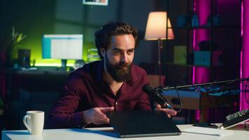 Influencer in studio endorsing laptop from brand sponsoring , talking in microphone. Content creator does influencer marketing by promoting notebook, recording with high tech mic, camera A video