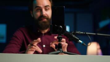 foco em Smartphone em anexo para tripé usava de conectados Estrela dentro embaçado fundo discutindo com espectadores. Móvel telefone usava de influenciador para registro social meios de comunicação , Câmera uma fechar acima video
