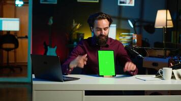 Tech specialist presenting chroma key tablet in entry level low budget price range to interested viewers, filming in studio. Viral content creator reviewing green screen digital device, camera A video