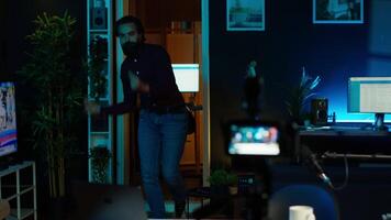 Content creator entering home studio, doing cool hand gesturing towards camera during live broadcast on online streaming platforms. Entertainer pointing fingers, captivating audience, camera A video