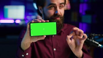 Cheerful man assessing mockup smartphone performance, feeling satisfied with high quality components used. Joyful content creator shooting mobile phone review for online channel, camera A close up video