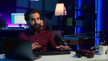 Man in studio reviewing gaming keyboard received from sponsoring brand. Online show host paid to promote bluetooth wireless computer peripheral to viewers during live broadcast, camera A video