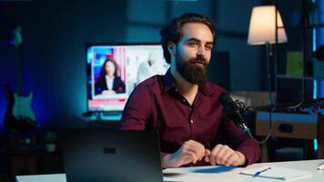 Content creator adjusting professional microphone in studio before starting recording for online vlogging channel. Man in neon lit home studio using equipment for vlog shooting, camera A video