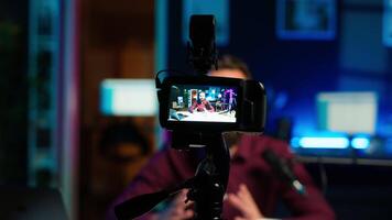 Content creator hosting online show in rgb lights studio, shooting vlog using professional gear. Vlogger presenting informations during streaming service broadcast filmed with camera, camera A video
