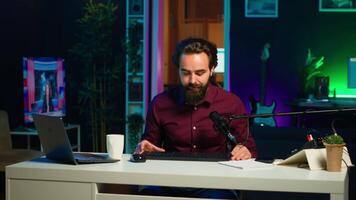 uomo le riprese per in linea canale nel debolmente illuminato casa studio, presentazione topo e tastiera per pubblico. soddisfare Creatore mostrando spettatori computer periferiche, dando onesto opinione, telecamera un' video