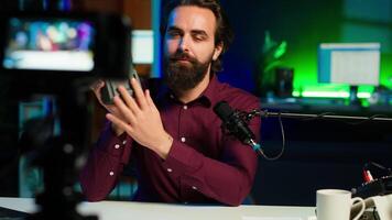 Portable V mount battery presented by knowledgeable tech professional to audience in studio. Lithium li ion charging device held by content creator doing presentation, camera A video