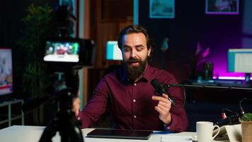 Smiling technology content creator filming review of newly launched gaming laptop, impressed by thinness. Internet star endorsing sponsor branded notebook to subscribers, camera A video