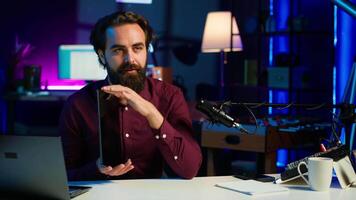 Entertaining man in studio films tablet review for tech enthusiasts. Viral media star hosts technology internet show, unboxing digital portable device, feeling impressed by thinness, camera A video
