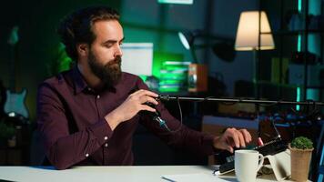 Portrait of upbeat content creator hosting online show in rgb lights studio, shooting vlog using professional microphone. Cheerful vlogger doing streaming service broadcast, camera A video
