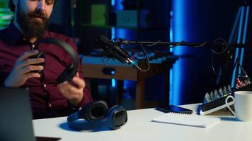 Tech expert testing headphones, review them for online streaming platforms. Professional audiophile hosts internet show, using sound mixer to check audio device sound sensitivity, camera A video