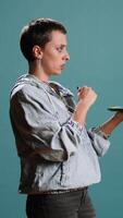 Vertical Modern tech person operating on tablet with a futuristic hologram, innovative visual graphics against blue background. Young woman looks at a holographic 3d image visualization. Camera A. video