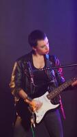 Vertical Female musical performer in a leather jacket plays electric guitar, delivering a fierce energetic music performance that captivates audience with her bold grunge style. Music lover. Camera B. video