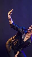 Vertical Rocker singer chatting on a call and showing the studio on a selfie camera, smartphone user recording her singing session. Cool edgy artist on live chat having a conversation. Camera B. video