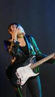 Vertical Female rock musician dealing with a painful headache while performing, feeling unwell and worried about her sickness. Artist rocker singing in discomfort from the migraine. Camera B. video