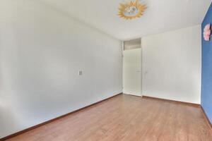 An empty room with a blue wall and wooden floors photo