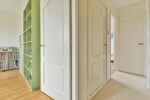 A hallway with two doors and a green bookcase photo