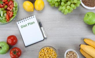 notebook with a diet plan with fresh vegetables and fruits on the table photo