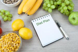 notebook with a diet plan with fresh vegetables and fruits on the table photo