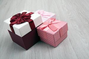 three colored gift boxes with bows on a gray wooden background photo