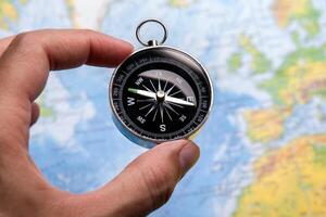 compass in the hand on the background of a map of the world photo