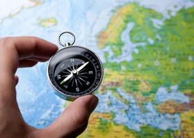 compass in the hand on the background of a map of the world photo