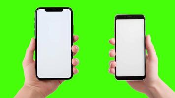 Two hands holding up two smartphones with blank screens on a green screen video