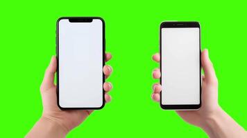 Two hands holding up two smartphones with blank screens on a green screen video