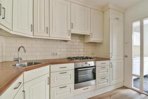 A kitchen with white cabinets and a wooden counter top photo