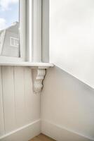 A corner of a room with a window and a shelf photo