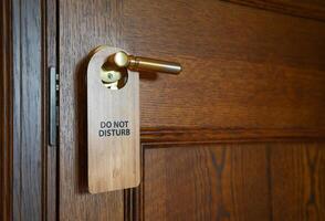 Please do not disturb sign hanging on the door handle in hotel room. photo