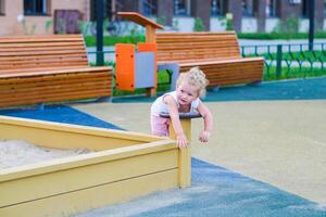 Child playing in the sandbox in the playground in the courtyard of a house photo