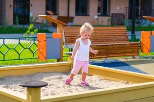Child playing in the sandbox in the playground in the courtyard of a house photo