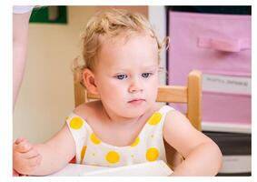 Beautiful blonde baby girl playing in kindergarten photo