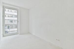 An empty room with a large window and white walls photo