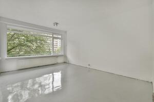 An empty room with a window and a white floor photo