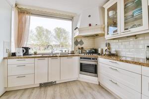 A kitchen with white cabinets and a window photo