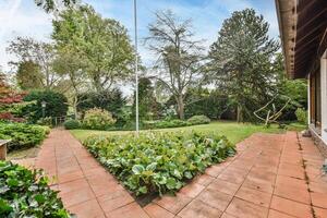 A garden with a brick walkway and trees photo