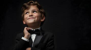 A young boy in a tuxedo looking up photo