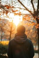 Solitary Figure Walks Through Autumn Forest at Sunset photo