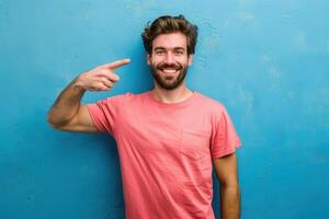 Portrait of a smiling man pointing finger on blue wall photo