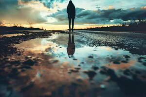 A person standing on a puddle in the middle of a road photo