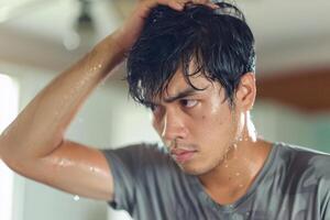 A man is standing in front of a mirror with his hair wet photo