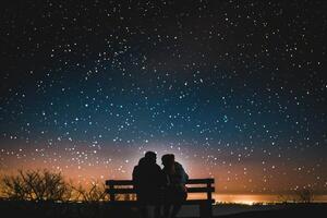 Two people sitting on a bench looking at the stars photo