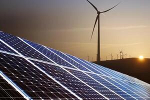 Solar panels and wind turbines at sunset photo