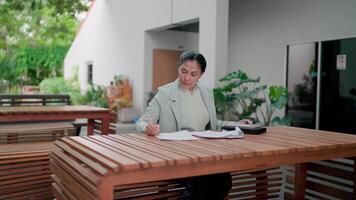 Asian professional businesswoman focusing on document review and using tablet while working outdoors, financial management, clerical work, data analyst, accountant, hustle and bussiness of business. video