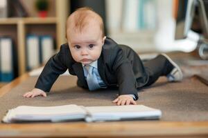 A baby in a suit crawling on the floor photo