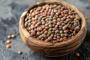 A wooden bowl filled with lentils on a dark surface photo