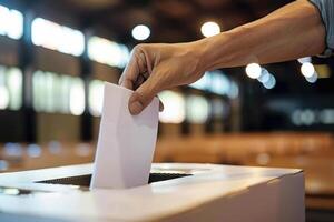A person putting a piece of paper into a voting box photo