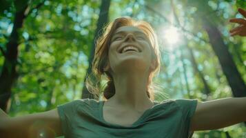 A woman is smiling in the forest with her arms outstretched photo