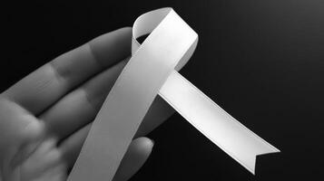 A hand holding a white ribbon photo